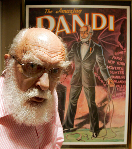 CORRECTS DAY OF DEATH TO TUESDAY, OCT. 20 INSTEAD OF MONDAY, OCT. 19 - FILE - In this Friday, June 29, 2007, file photo, James Randi is shown in front of a poster at his home in Fort Lauderdale, Fla. The Florida-based James Randi Educational Foundation announced its founder died Tuesday, Oct. 20, 2020, at 92. (AP Photo/Alan Diaz, File)