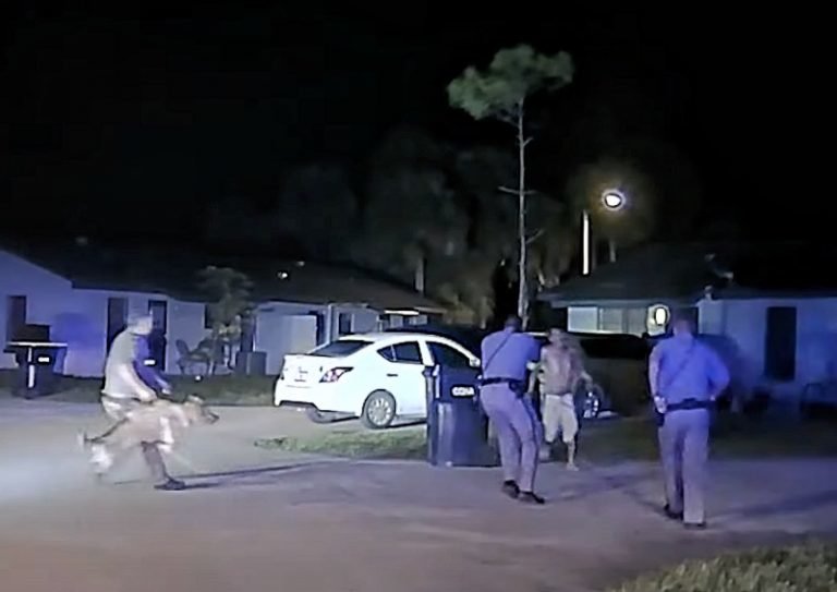 The image is a still from the police dashcam video showing the moment when Cpl. Pierre Jean (center) shoots Nicolas Morales four times at short range.
