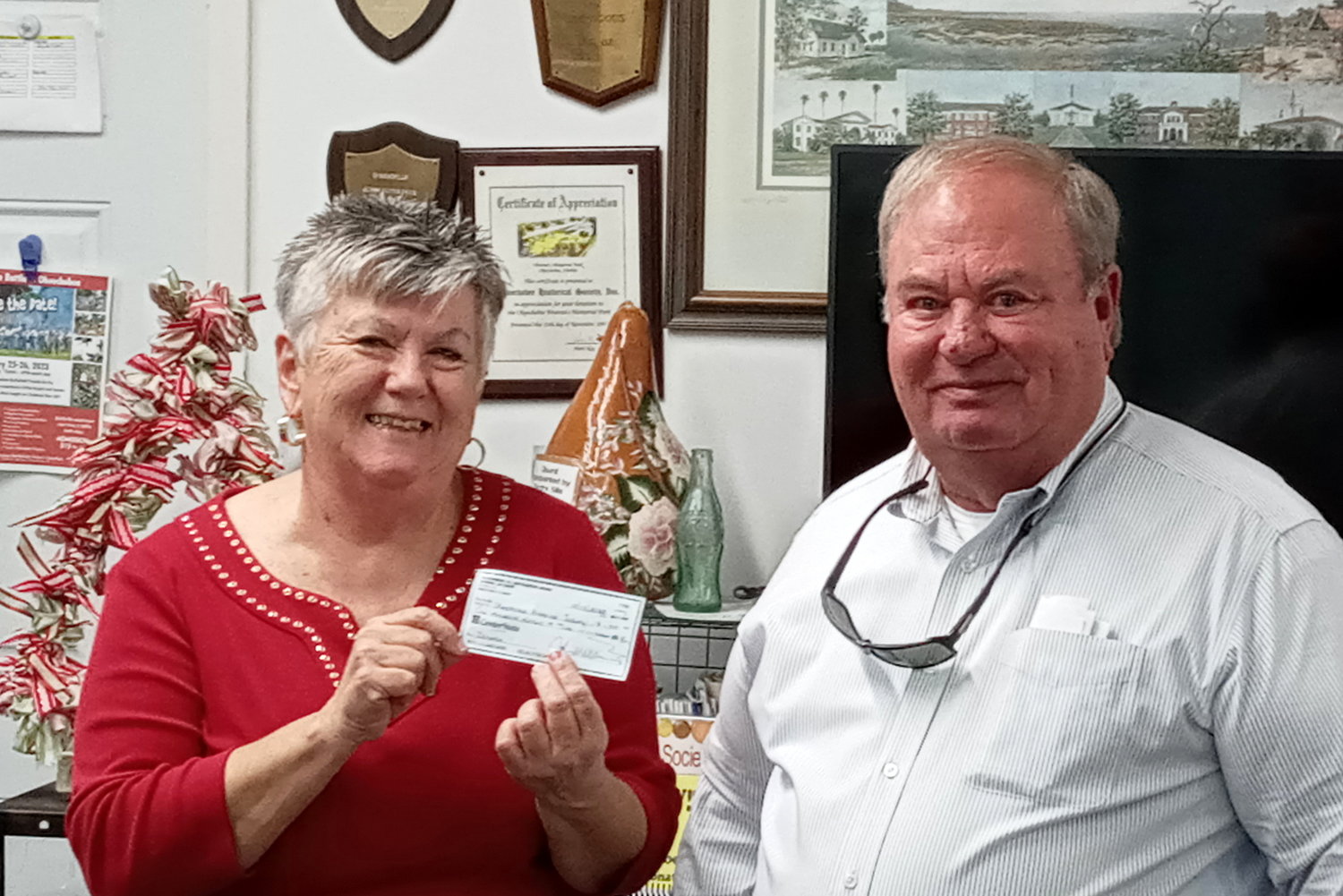 Magi Cable accepts a $1,000 check from John Williams, representative of the Okeechobee Cattlemen’s Association to be used in the development of an agriculture museum.