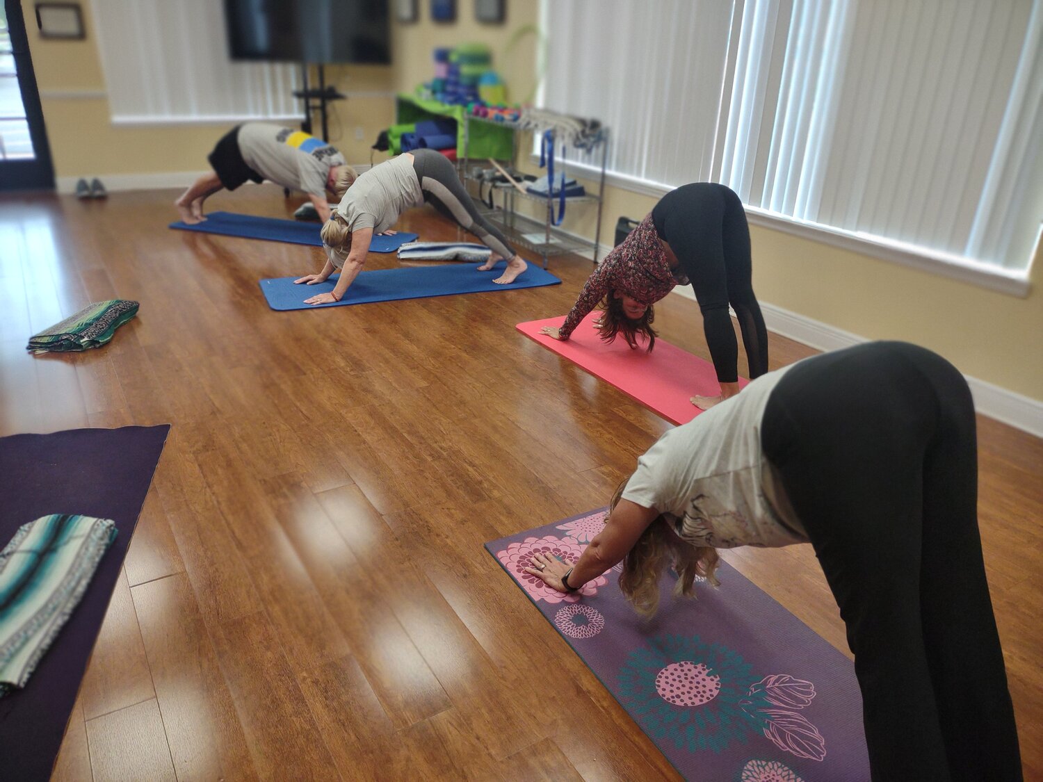Nancy Peterson, Inni Whitmill, Elizabeth Barrios and Elvis Gronoff demonstrate the downward dog position.